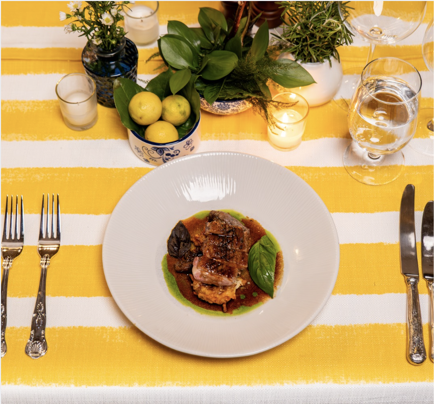 a plate of food on a table with a yellow and white tablecloth