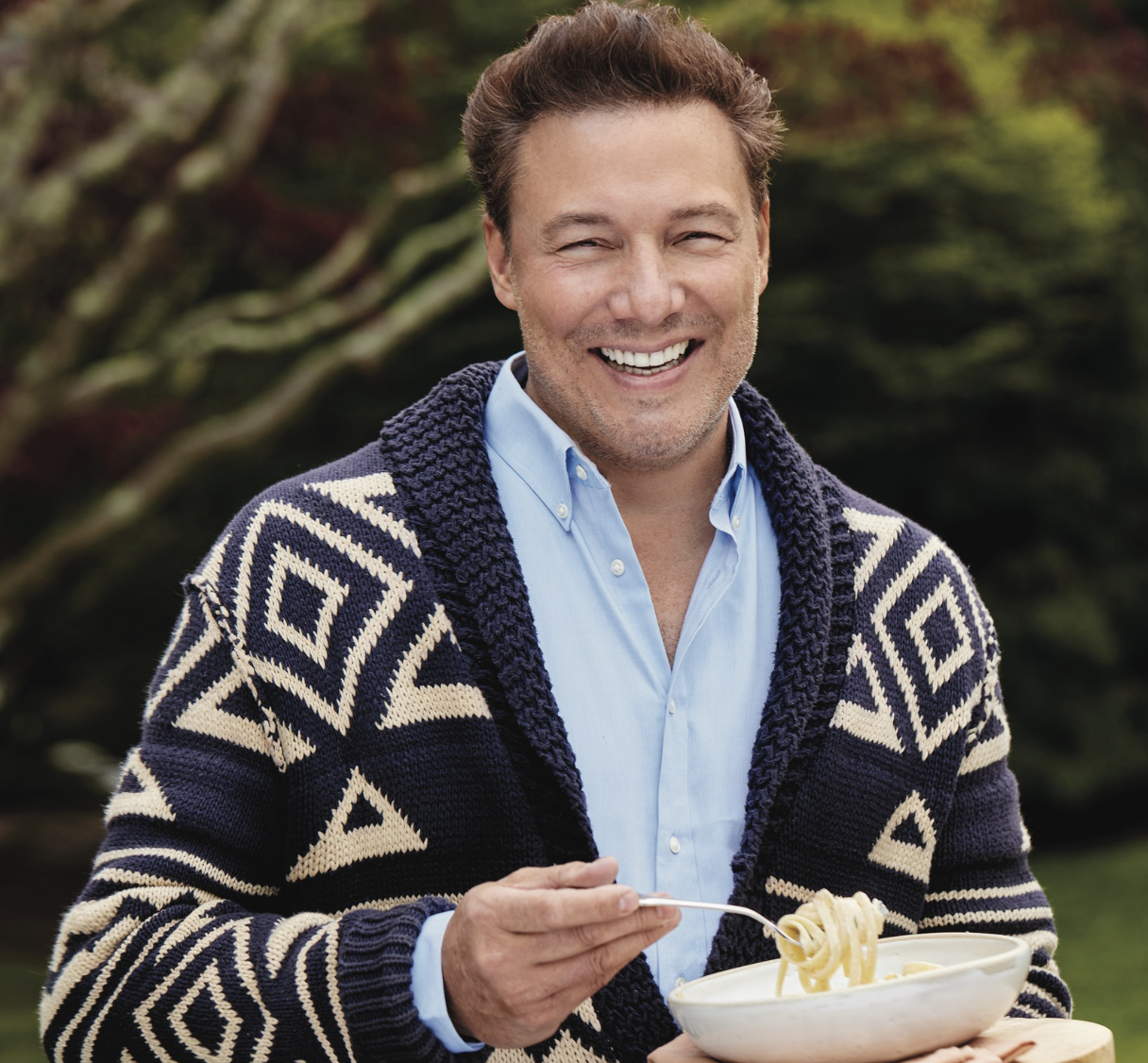 a man smiling while holding a bowl of food