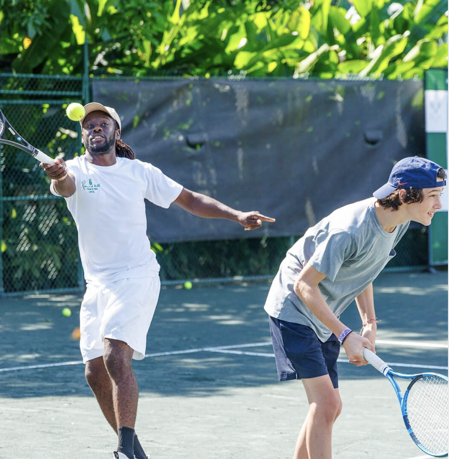 a man pointing at a tennis ball with his racket