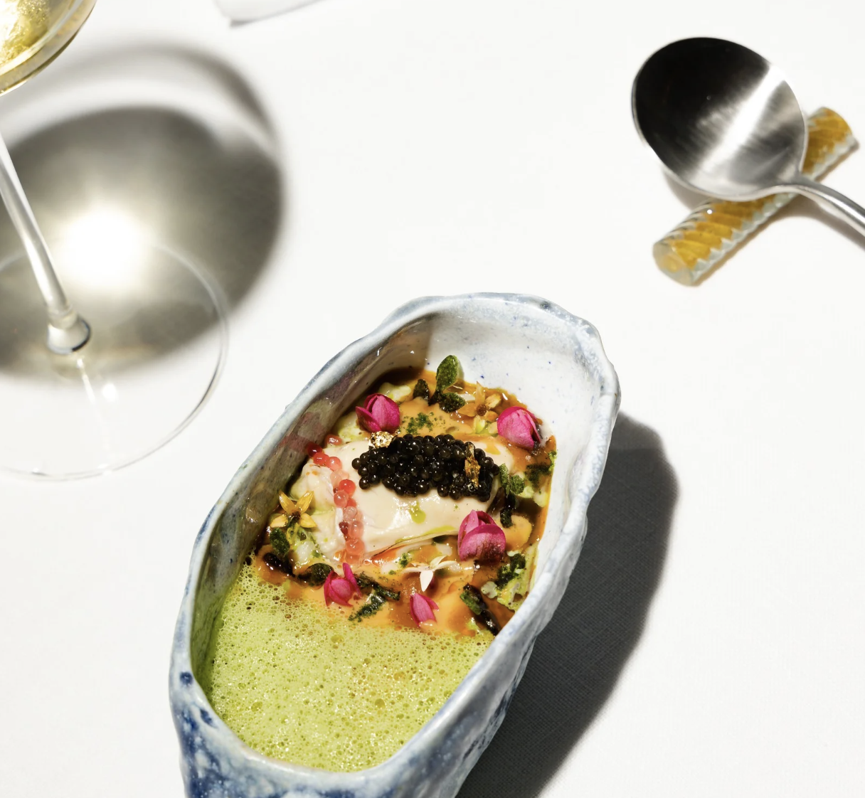 a bowl of food next to a glass of wine