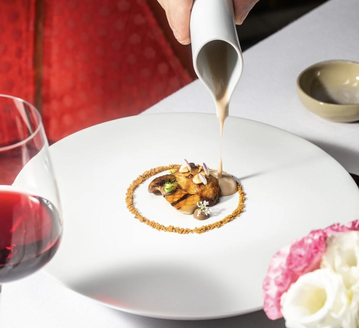 a person pouring sauce on a plate