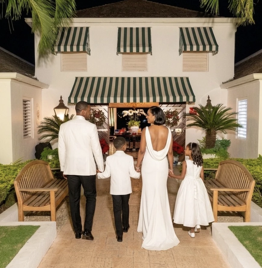 a man and woman in white dress walking down a walkway