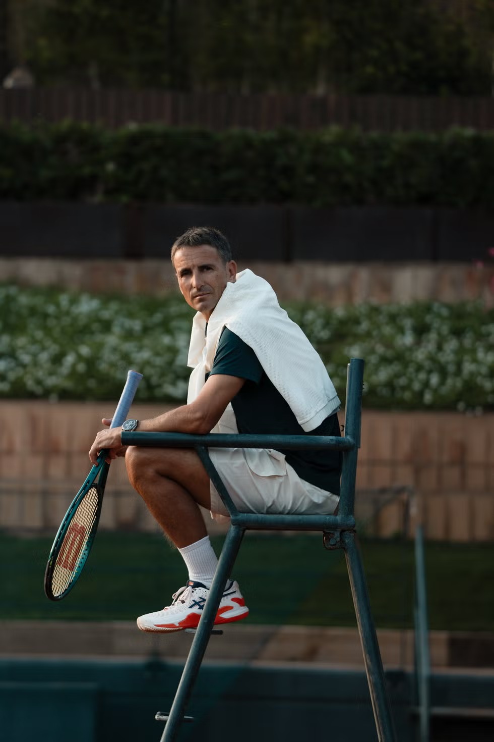 a man sitting on a chair with a tennis racket