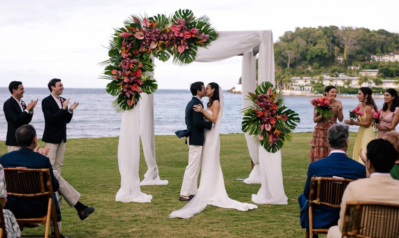 a man and woman kissing under a floral arch