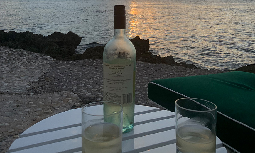 a bottle of wine on a table with glasses on a beach