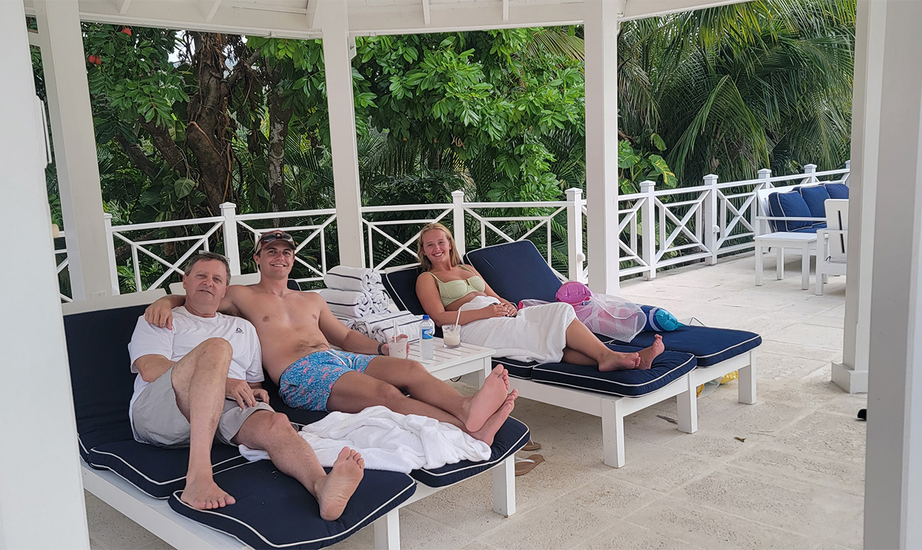a group of people sitting on lounge chairs under a white fence