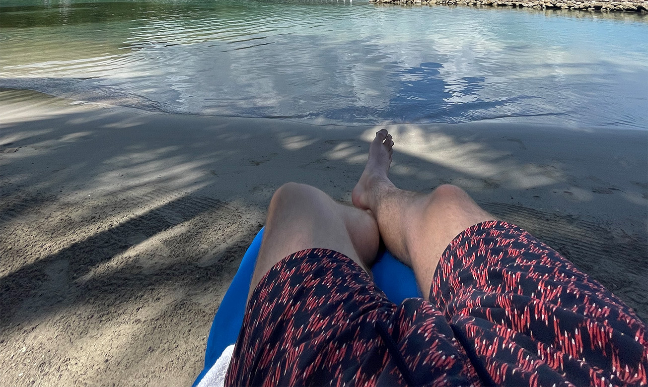 a person lying on a blue float on the beach