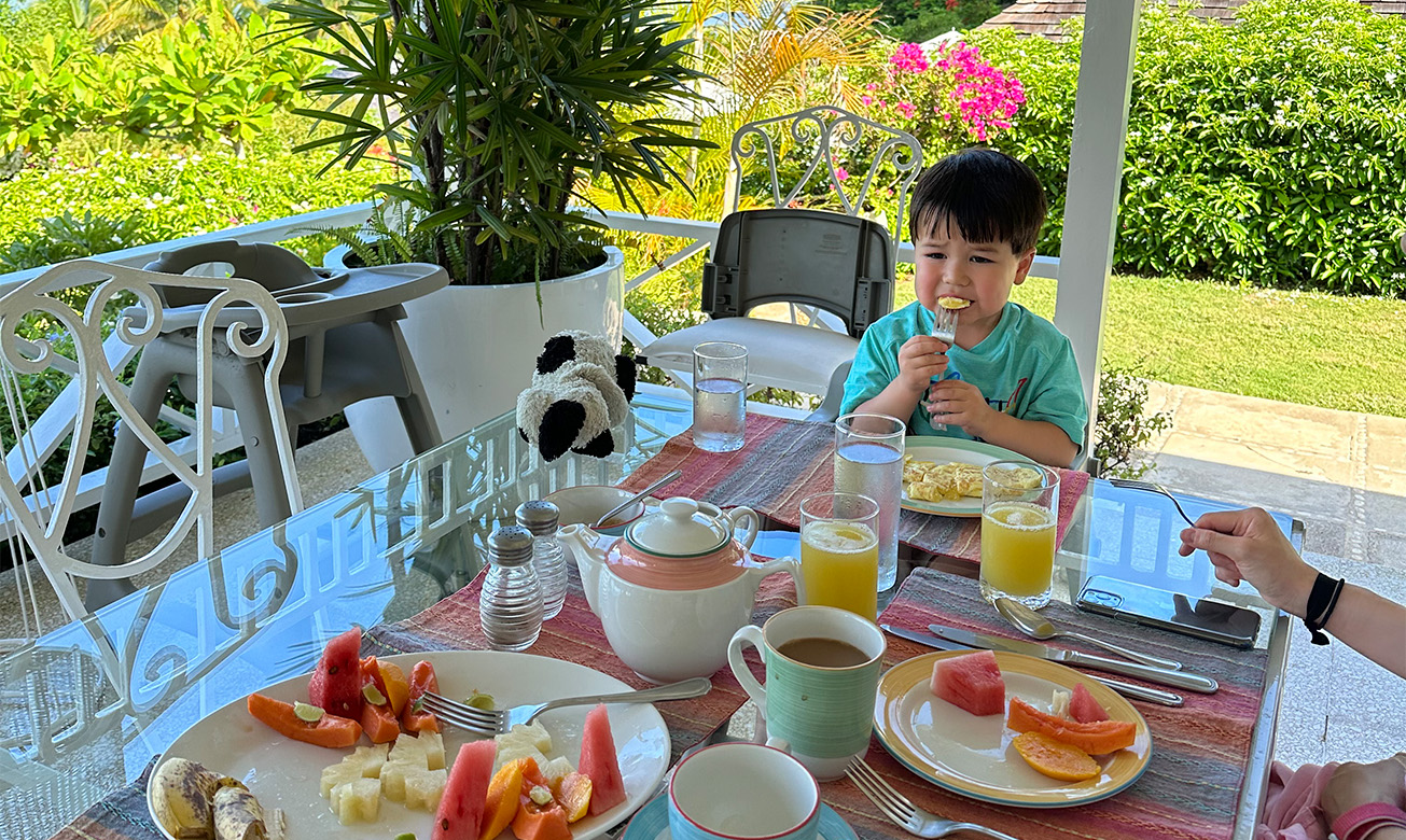 a boy eating at a table with food and drinks