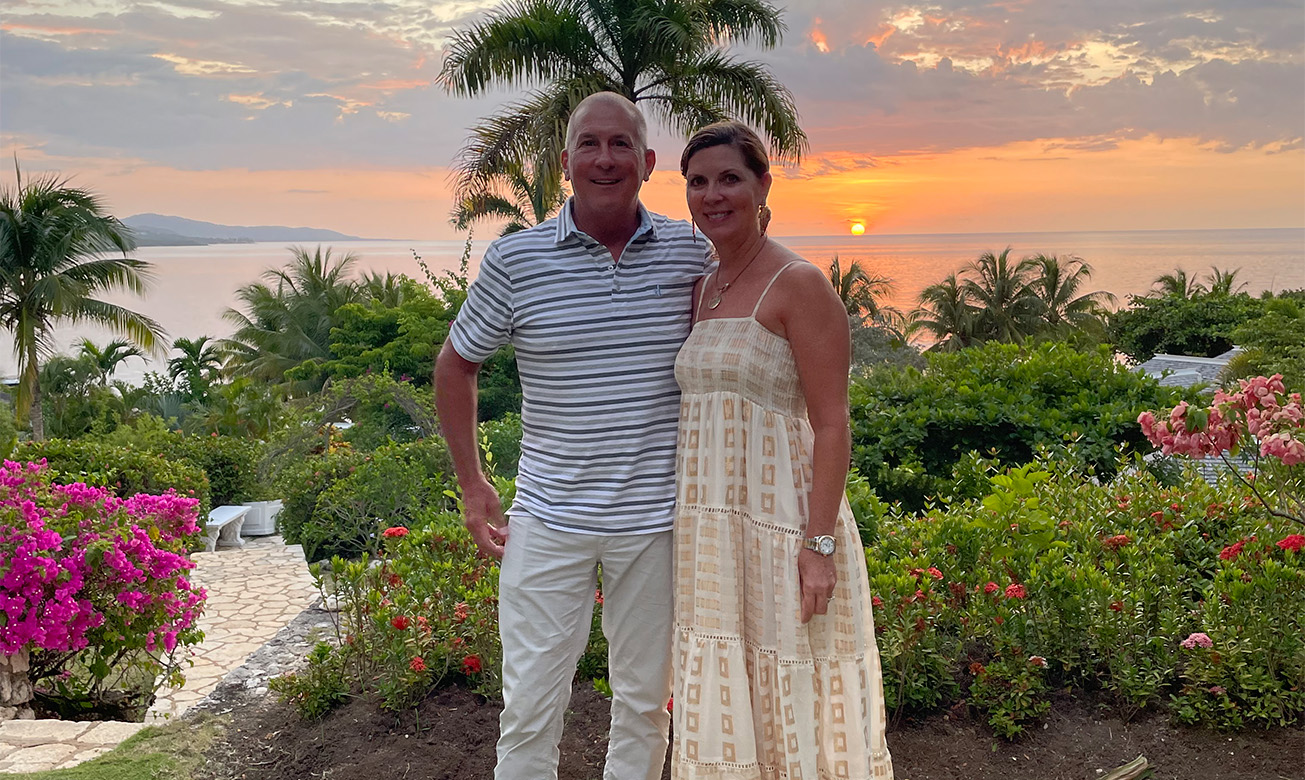 a man and woman standing in front of a palm tree