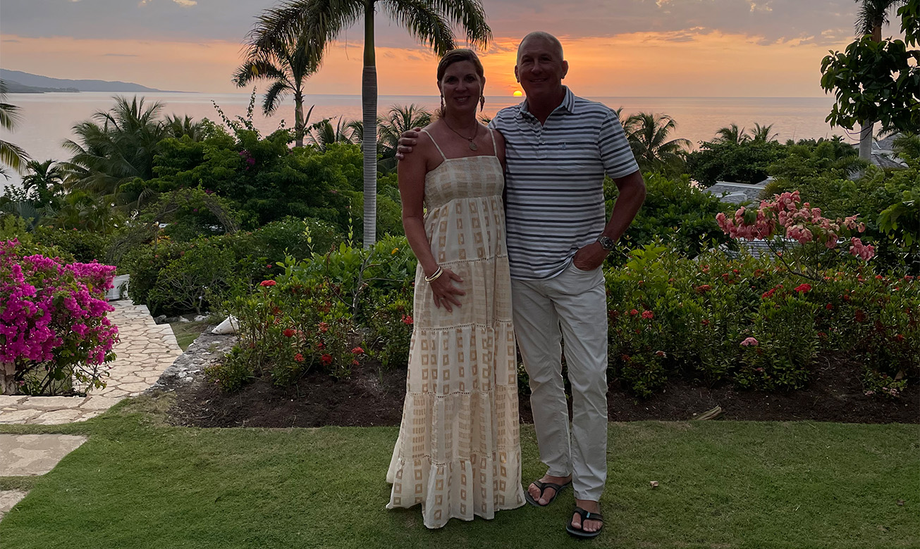 a man and woman standing in front of palm trees
