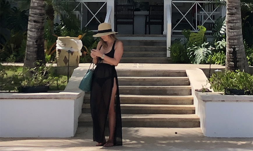 a woman in a black dress and hat standing on steps