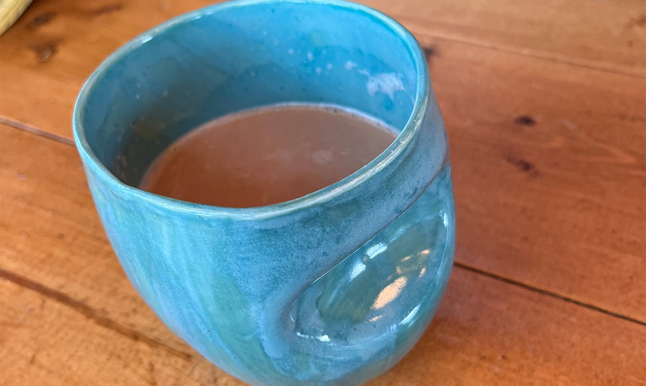 a blue mug with a brown liquid in it