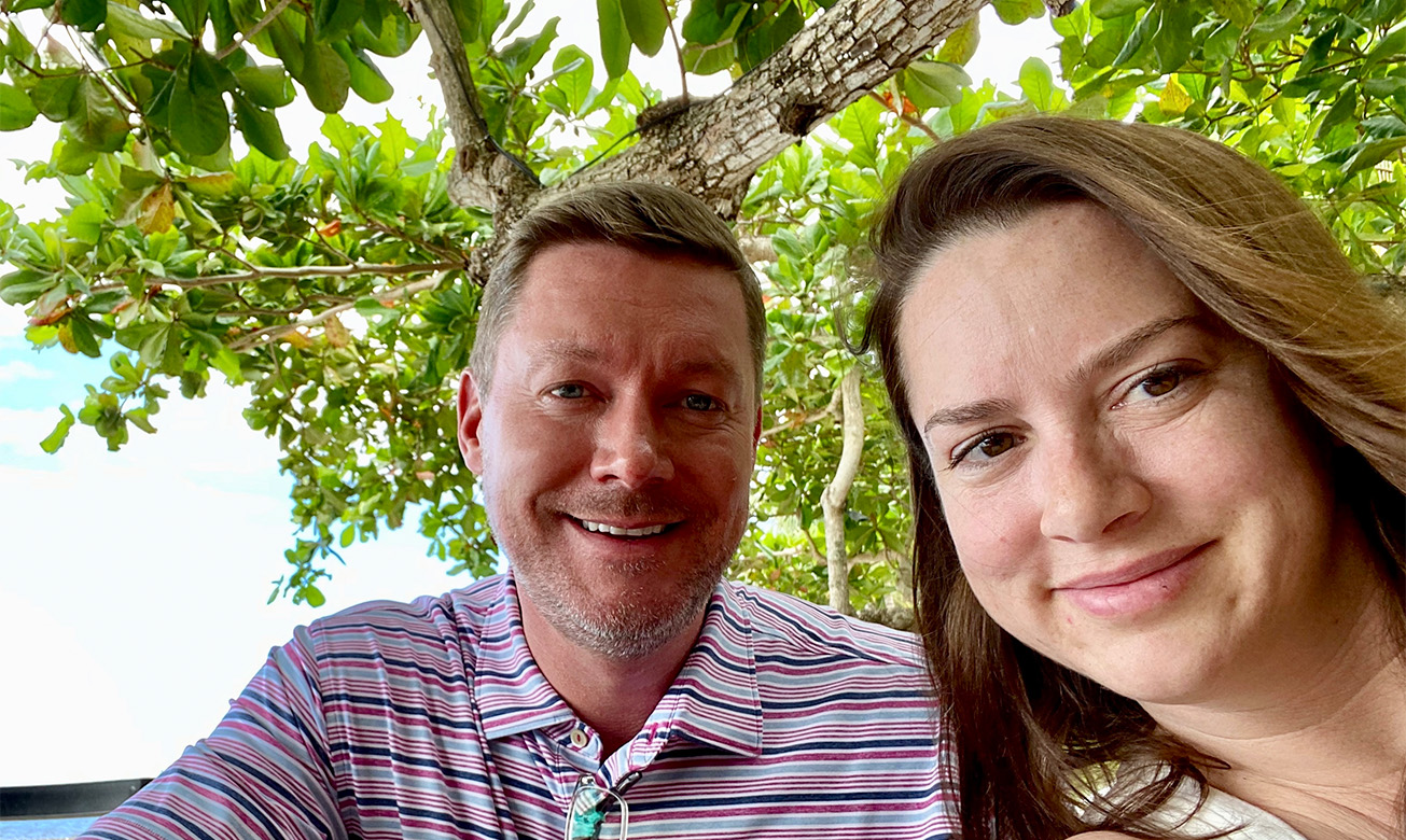 a man and woman taking a selfie under a tree