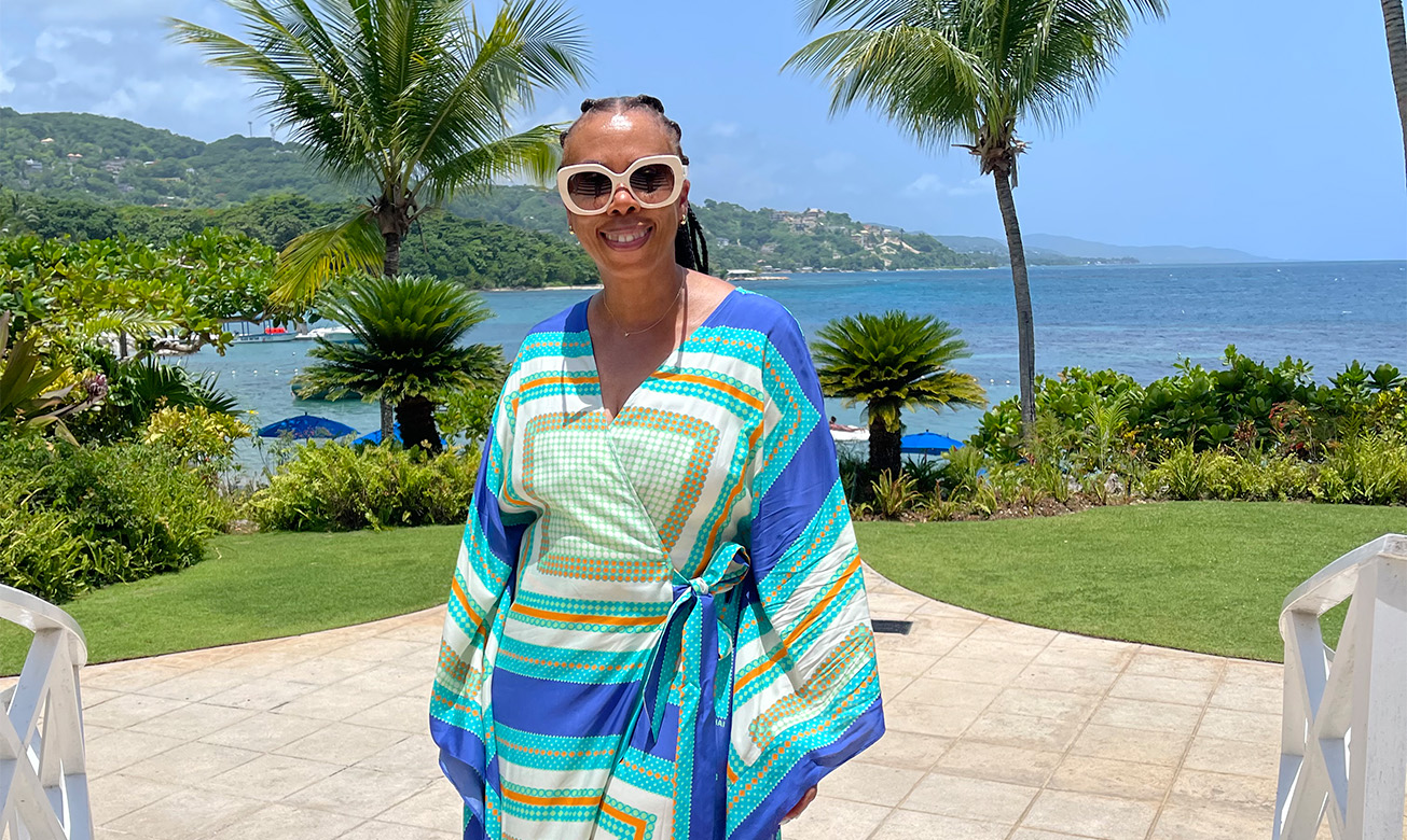 a woman wearing sunglasses and a beach robe standing on a sidewalk