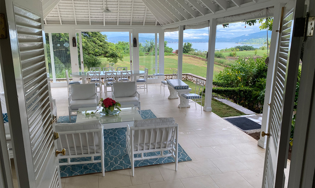 a white patio with chairs and tables and a view of a lake