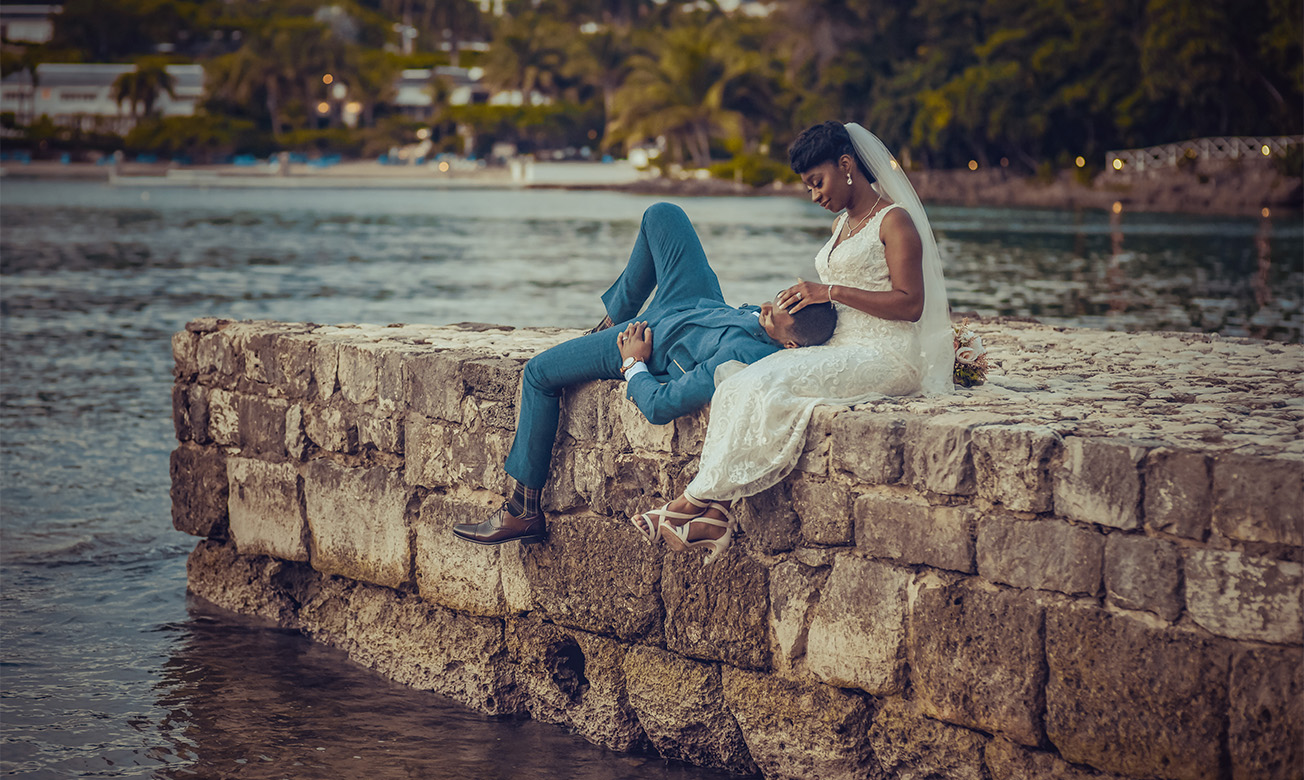 a man and woman sitting on a stone wall
