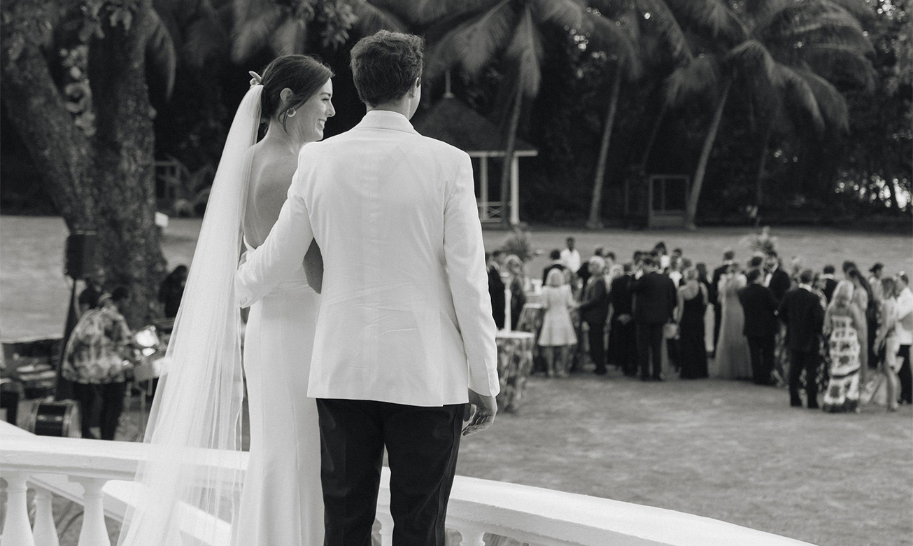 a man and woman standing on a balcony looking at a crowd of people