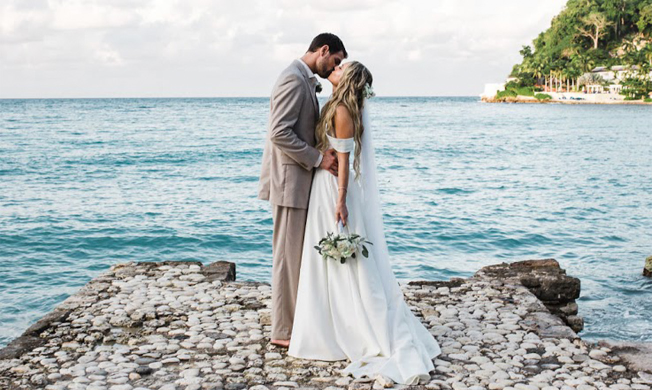 a man and woman kissing on a rocky beach