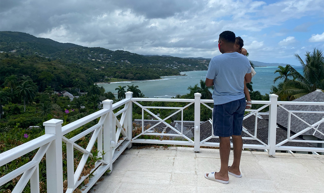 a man and baby standing on a balcony overlooking a body of water