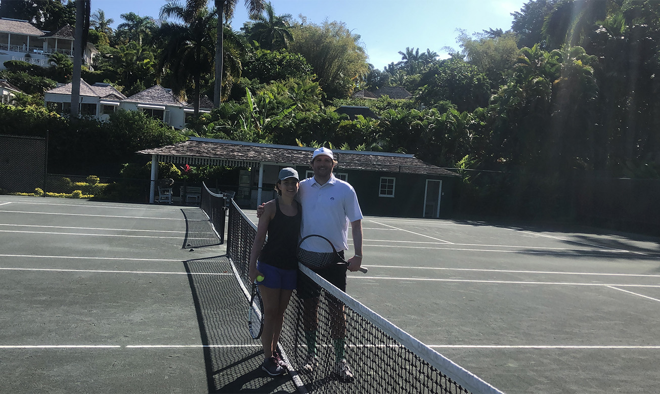 a man and woman standing next to a tennis net