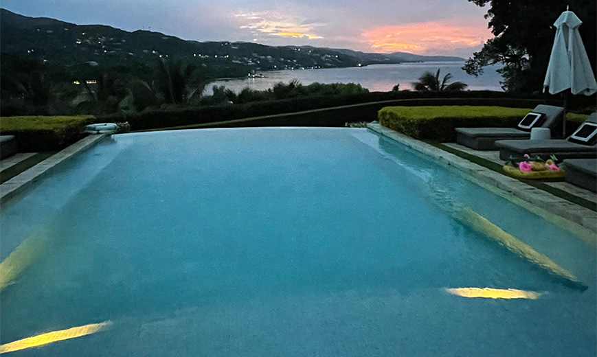a pool with a view of the ocean and mountains