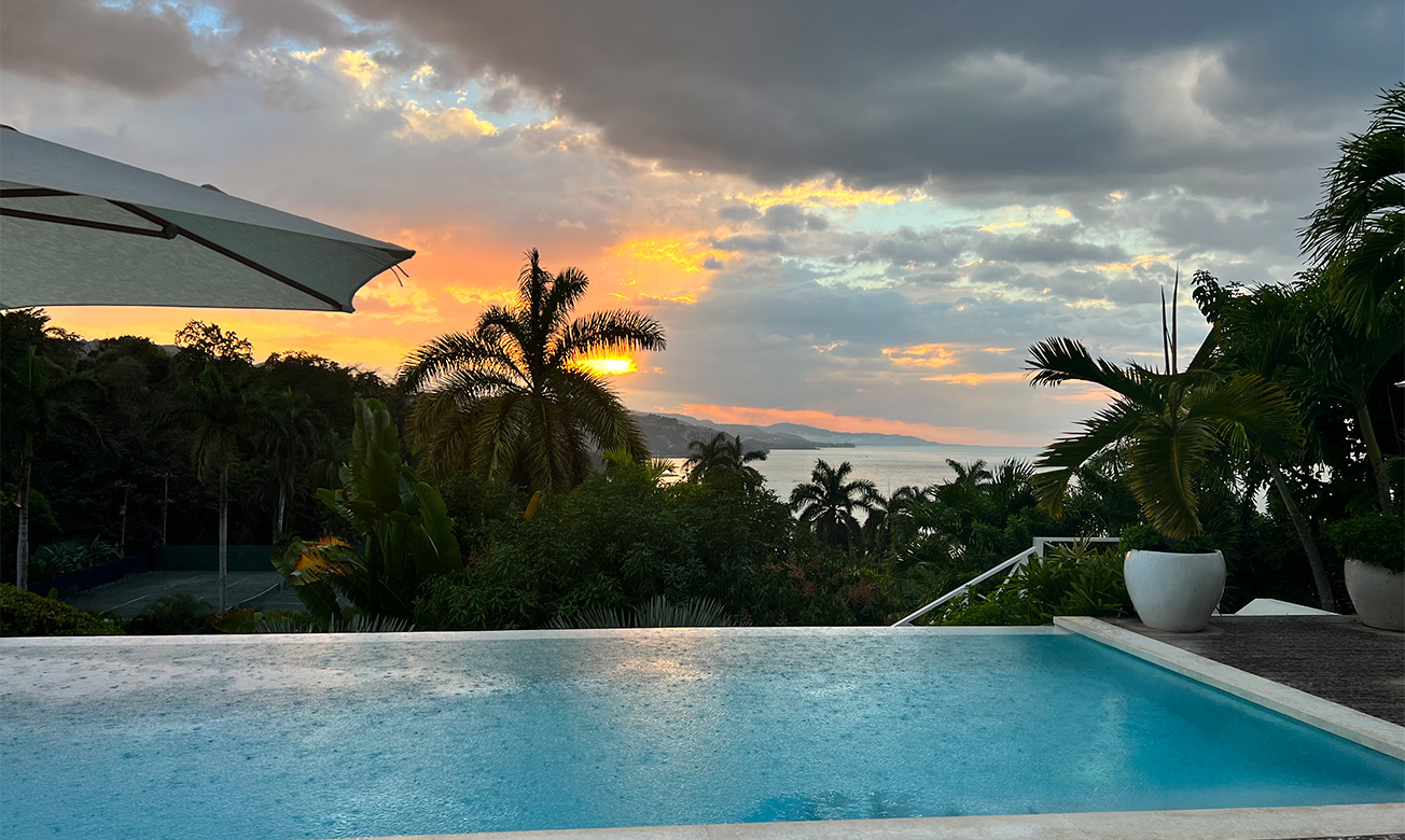 a pool with trees and a sunset