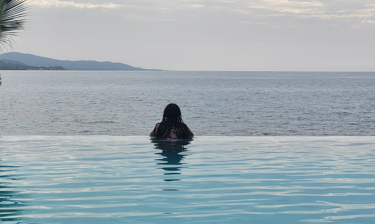 a woman sitting in a pool overlooking the ocean