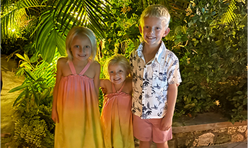 a group of children standing in front of a plant