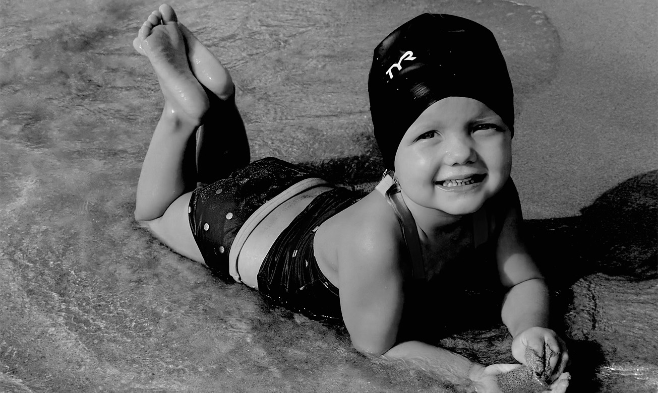 a child lying on the sand at the beach