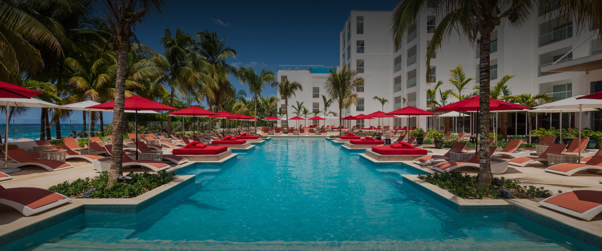 a pool with lounge chairs and umbrellas by a building