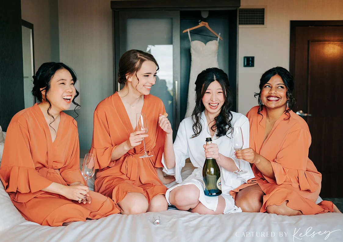 a group of women sitting on a bed with wine glasses and champagne