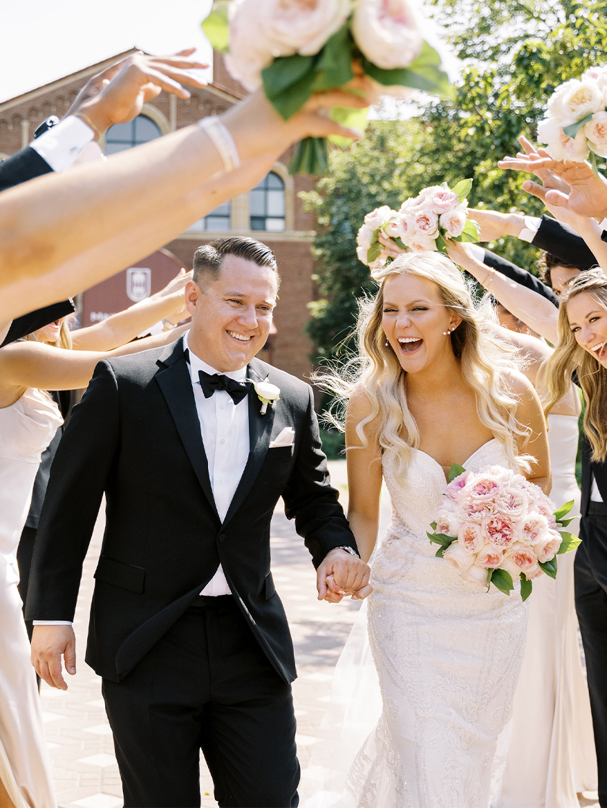a man and woman in white dresses walking with a group of people