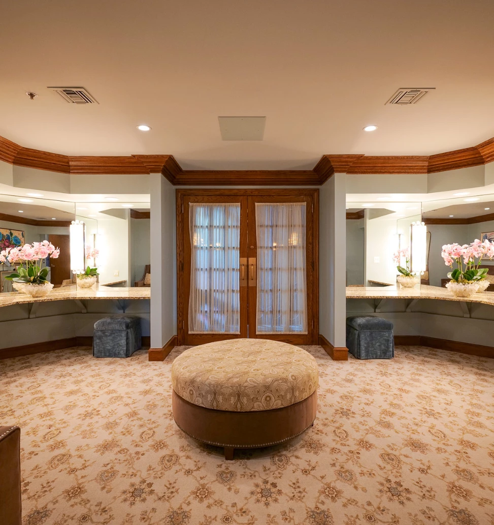 a room with a round stool and two mirrors