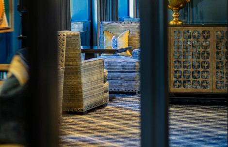 a room with a blue and white patterned couch and a vase of flowers