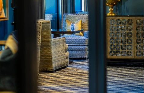 a room with a blue and white patterned couch and a vase of flowers