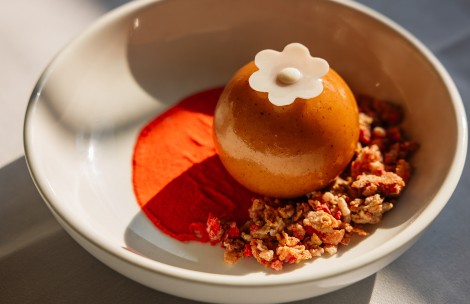 a round object with a flower on top on a white plate with red powder