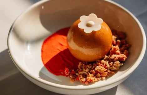 a round object with a flower on top on a white plate with red powder