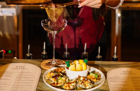 a person pouring a drink into a martini glass