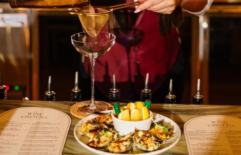 a person pouring a drink into a martini glass