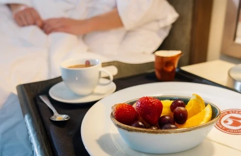 a bowl of fruit and a cup of coffee on a tray