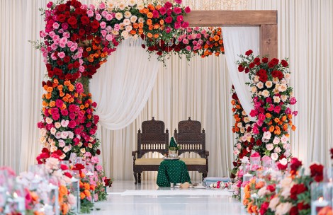 a flower arch with a table and chairs