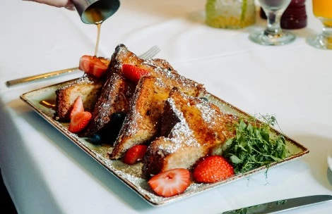 a plate of french toast with strawberries and sprinkles