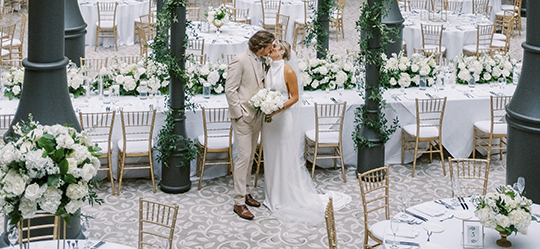 a man and woman kissing in a room with tables and chairs