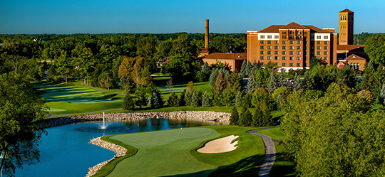 a golf course with a building and a pond