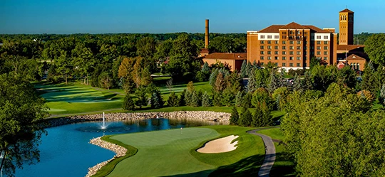 a golf course with a building and a pond
