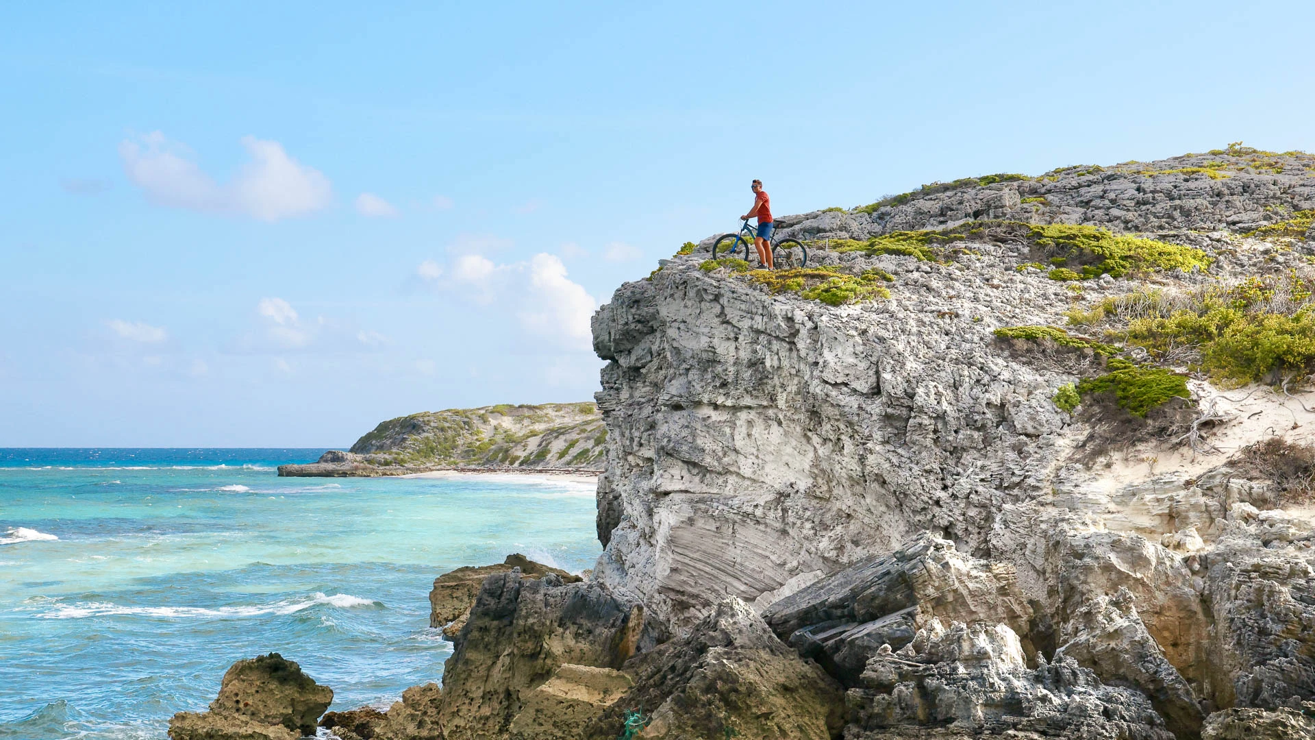 a man standing on a rocky cliff next to a body of water