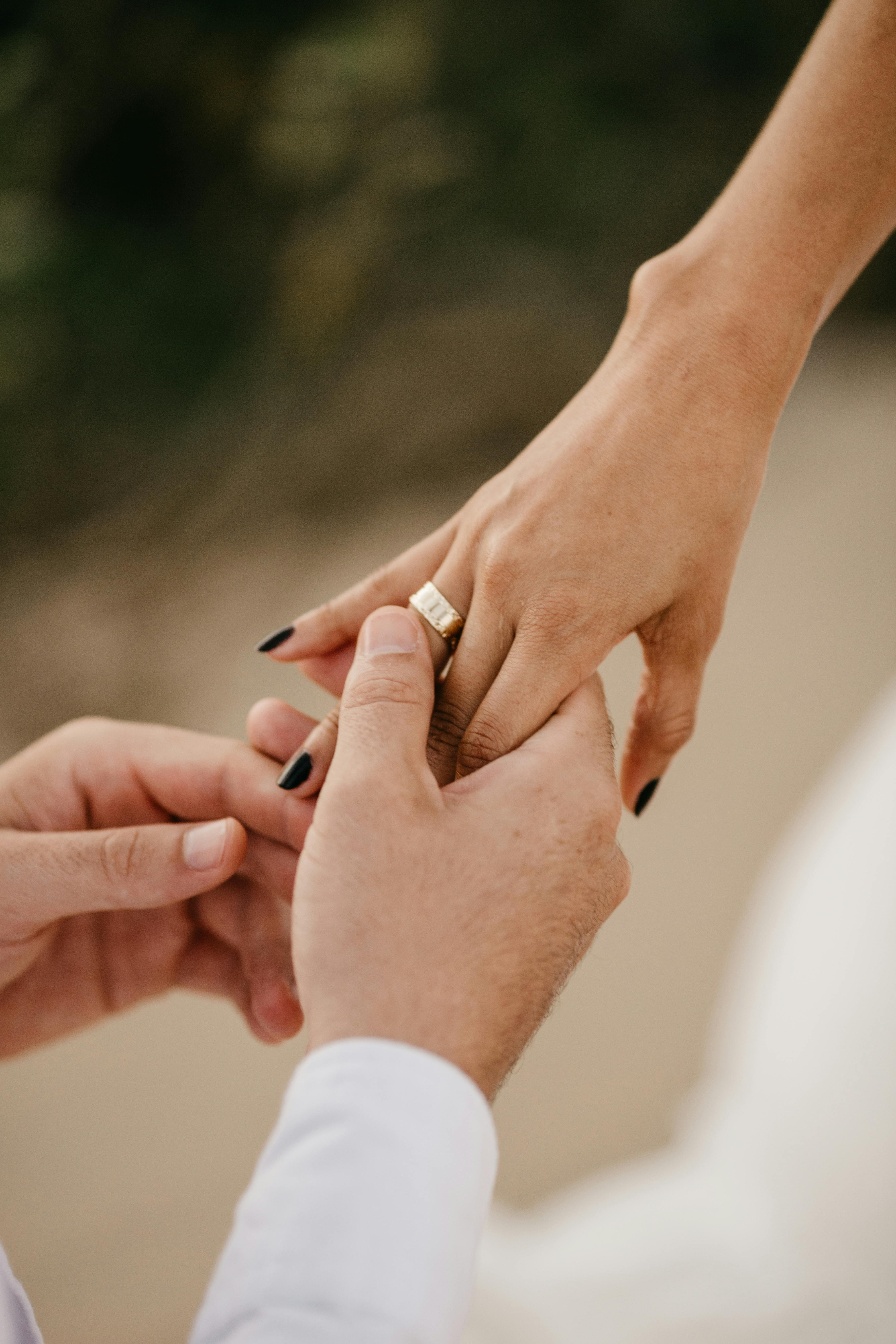 a man putting a ring on a woman's finger