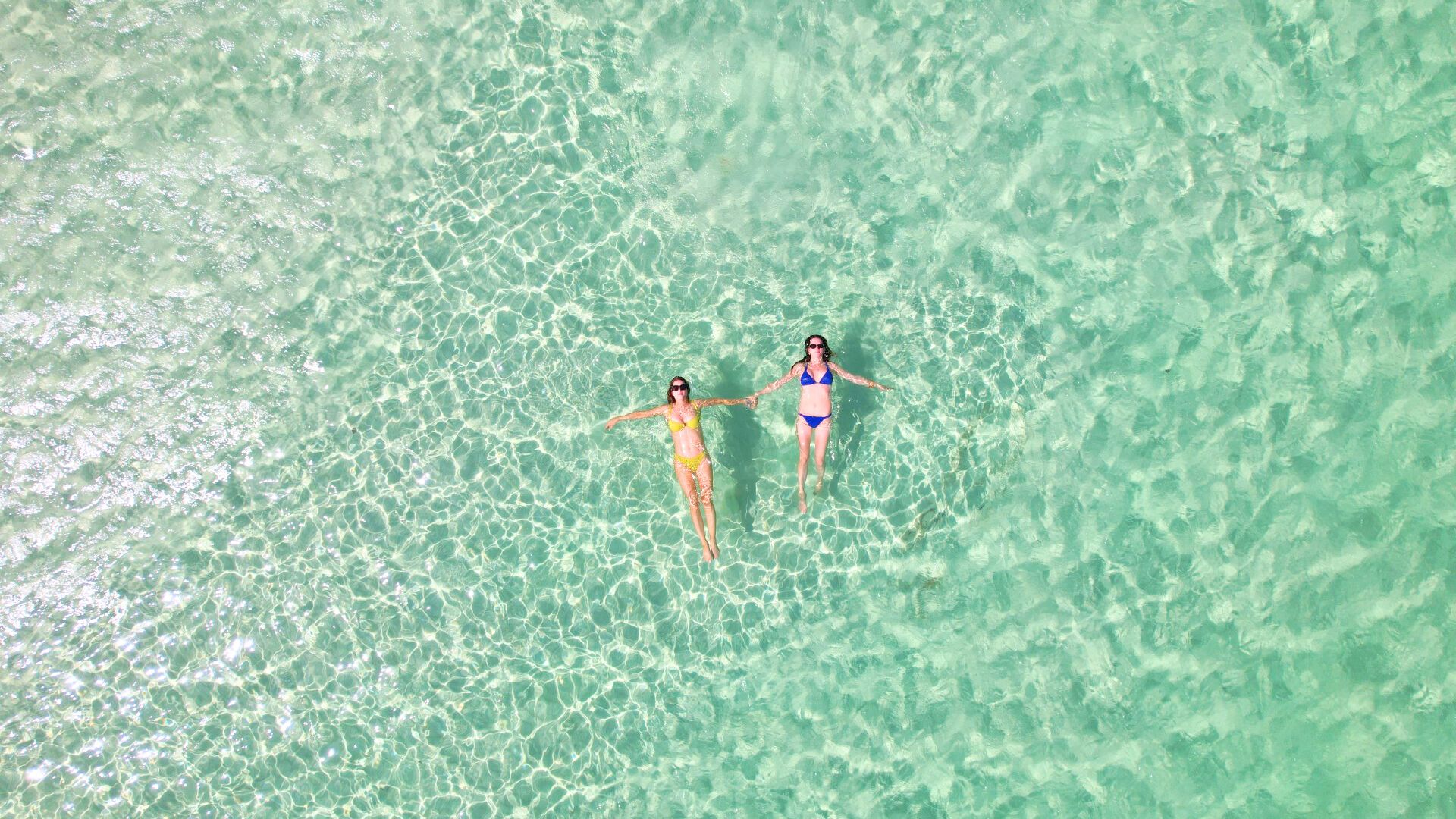 two women in garments floating in clear water