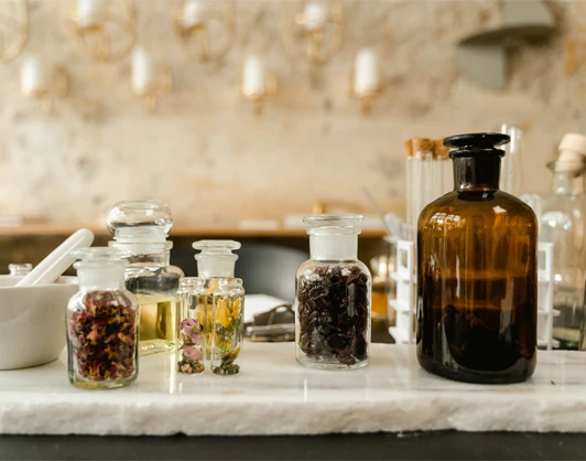 a group of glass bottles with herbs and spices on a white surface