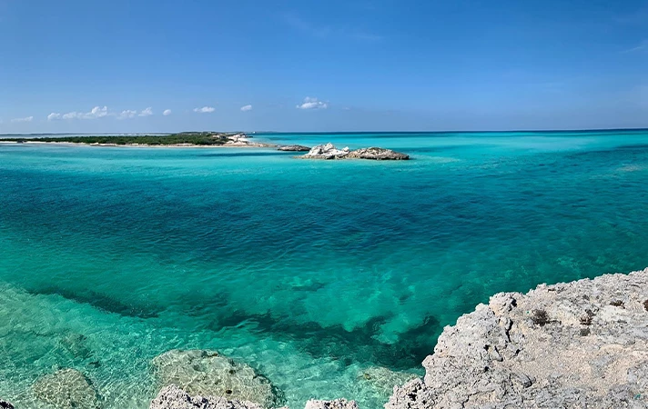 a blue water with rocks and land in the distance